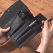 A person holding a stylus and a black case.